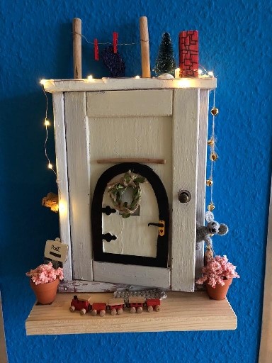 Weihnachtlich geschmückte Modell-Haustür mit Lichterkette