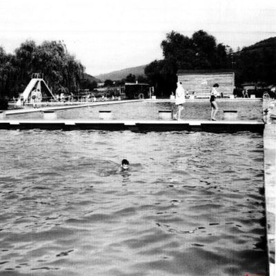 schwarz-weiß Fotografie des Freibades; Junge schwimmt durch Becken